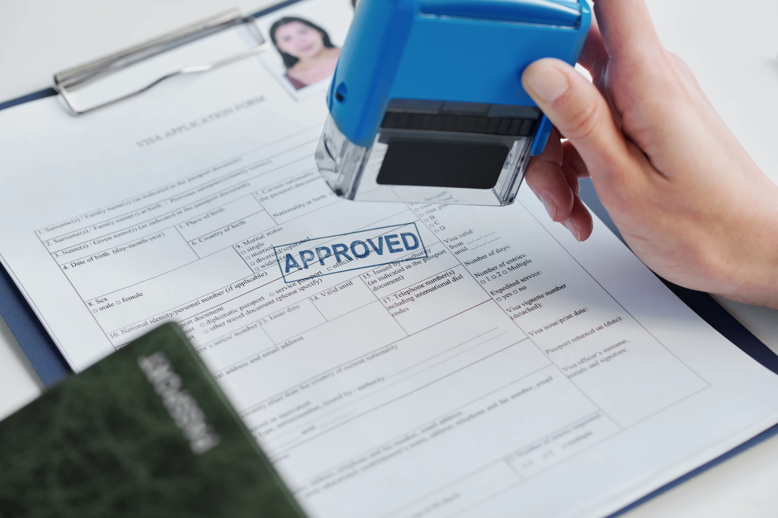 Hand stamping "APPROVED" on U Visa form with passport visible