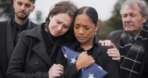 Grieving immigrant woman holding folded American flag surrounded by mourners, symbolizing loss and immigration struggle