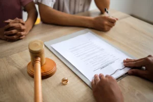 Reviewing divorce agreement with gavel and wedding rings on table