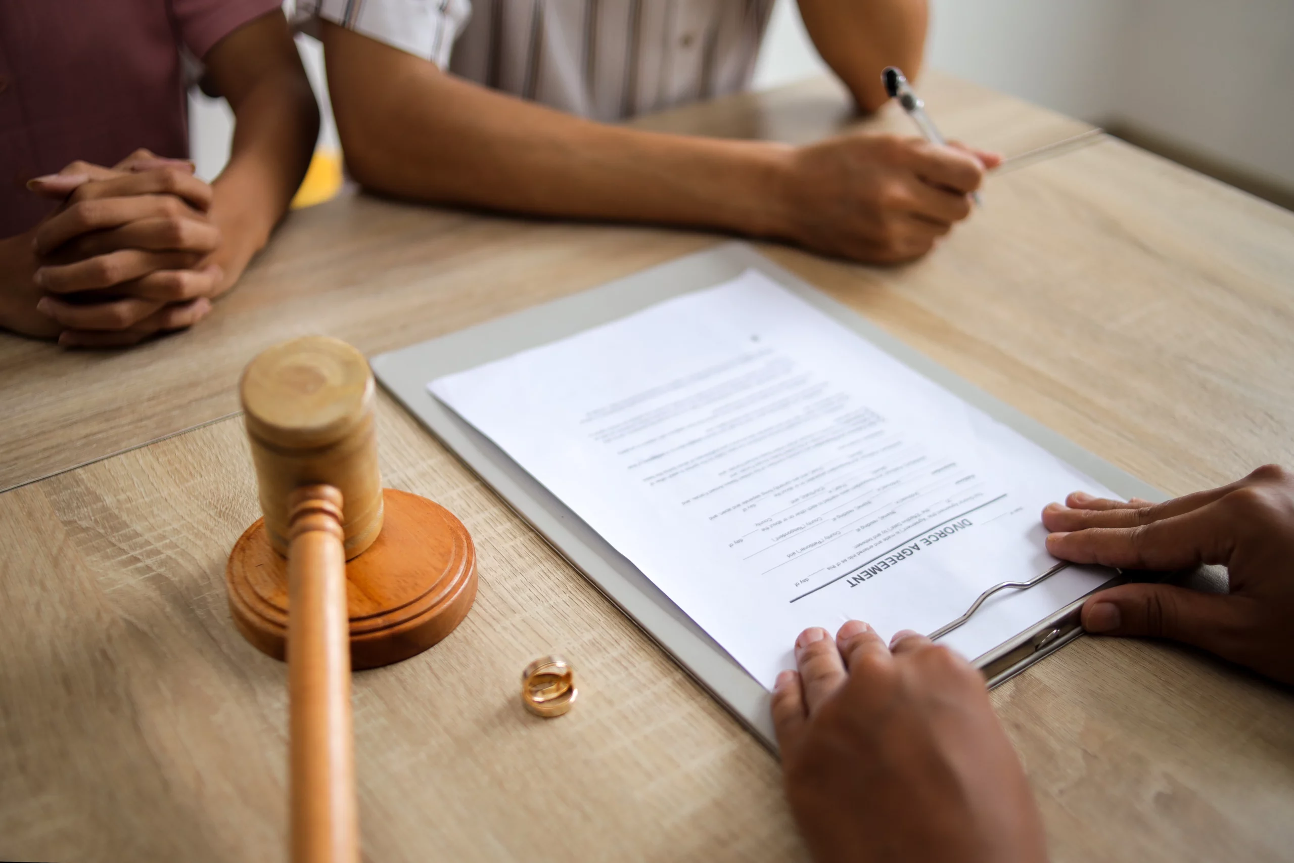 Reviewing divorce agreement with gavel and wedding rings on table