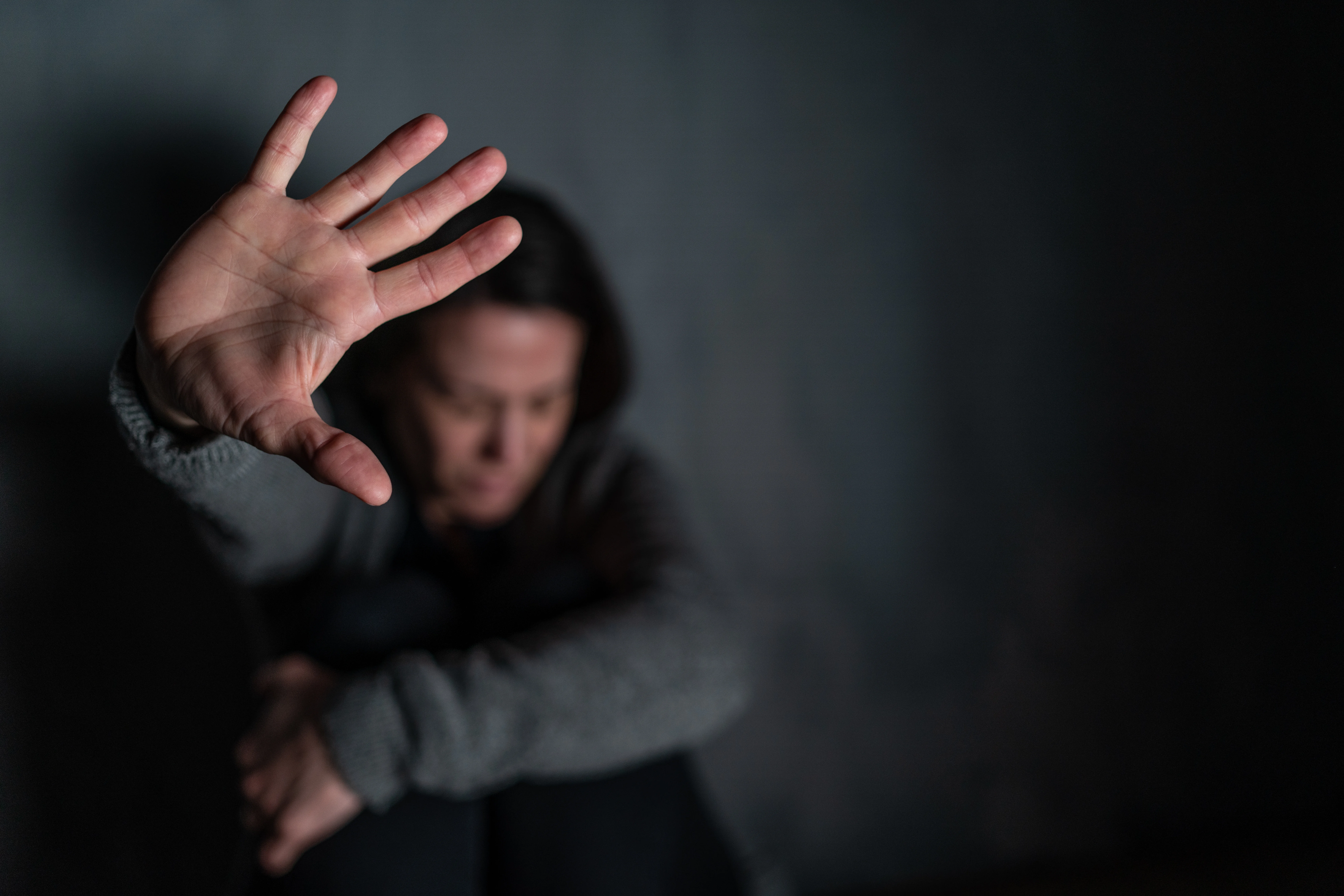 Distressed person in dark room with outstretched hand, illustrating human trafficking victim eligible for a T visa and legal protection in New Jersey.