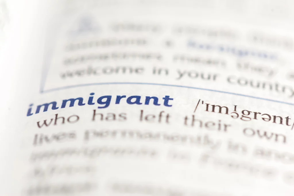 Close‑up of dictionary page showing word ‘immigrant,’ illustrating Special Immigrant Juvenile Status (SIJS) benefits for children in U.S. immigration law.