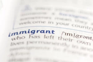 Close‑up of dictionary page showing word ‘immigrant,’ illustrating Special Immigrant Juvenile Status (SIJS) benefits for children in U.S. immigration law.