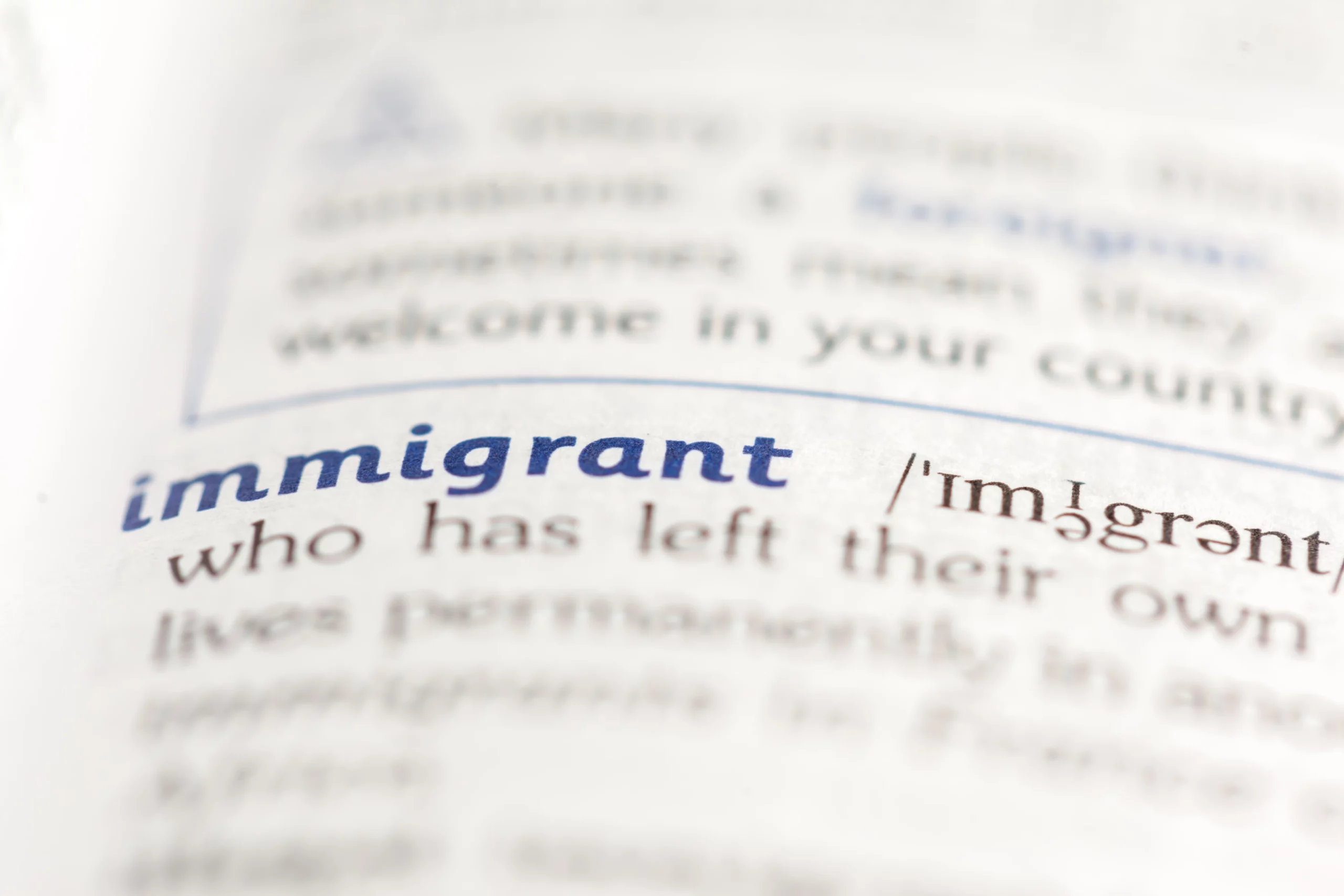 Close‑up of dictionary page showing word ‘immigrant,’ illustrating Special Immigrant Juvenile Status (SIJS) benefits for children in U.S. immigration law.